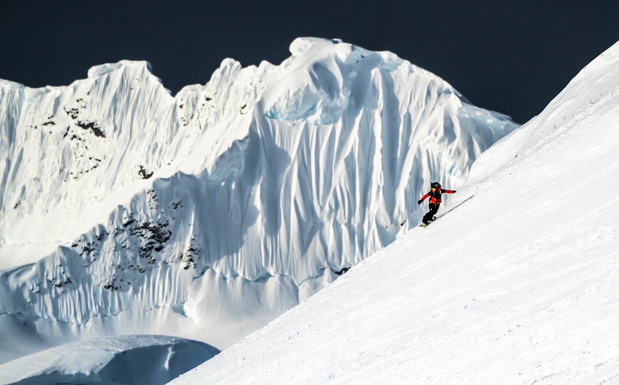 Skier below towering ice cliffs in Antarctica