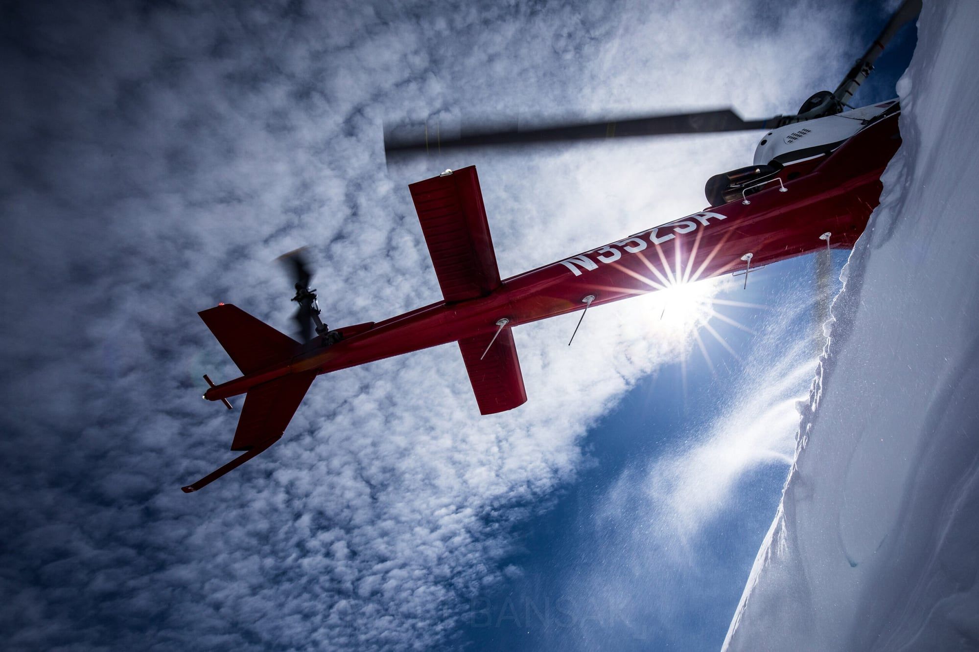 Red helicopter underside against a sunburst