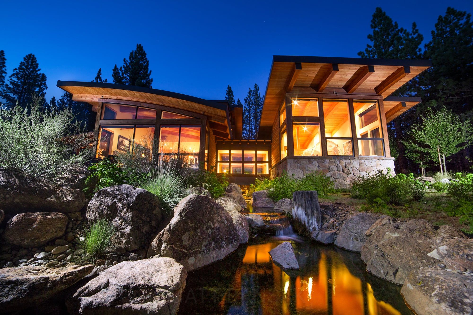 Modern home glowing at twilight over a pond