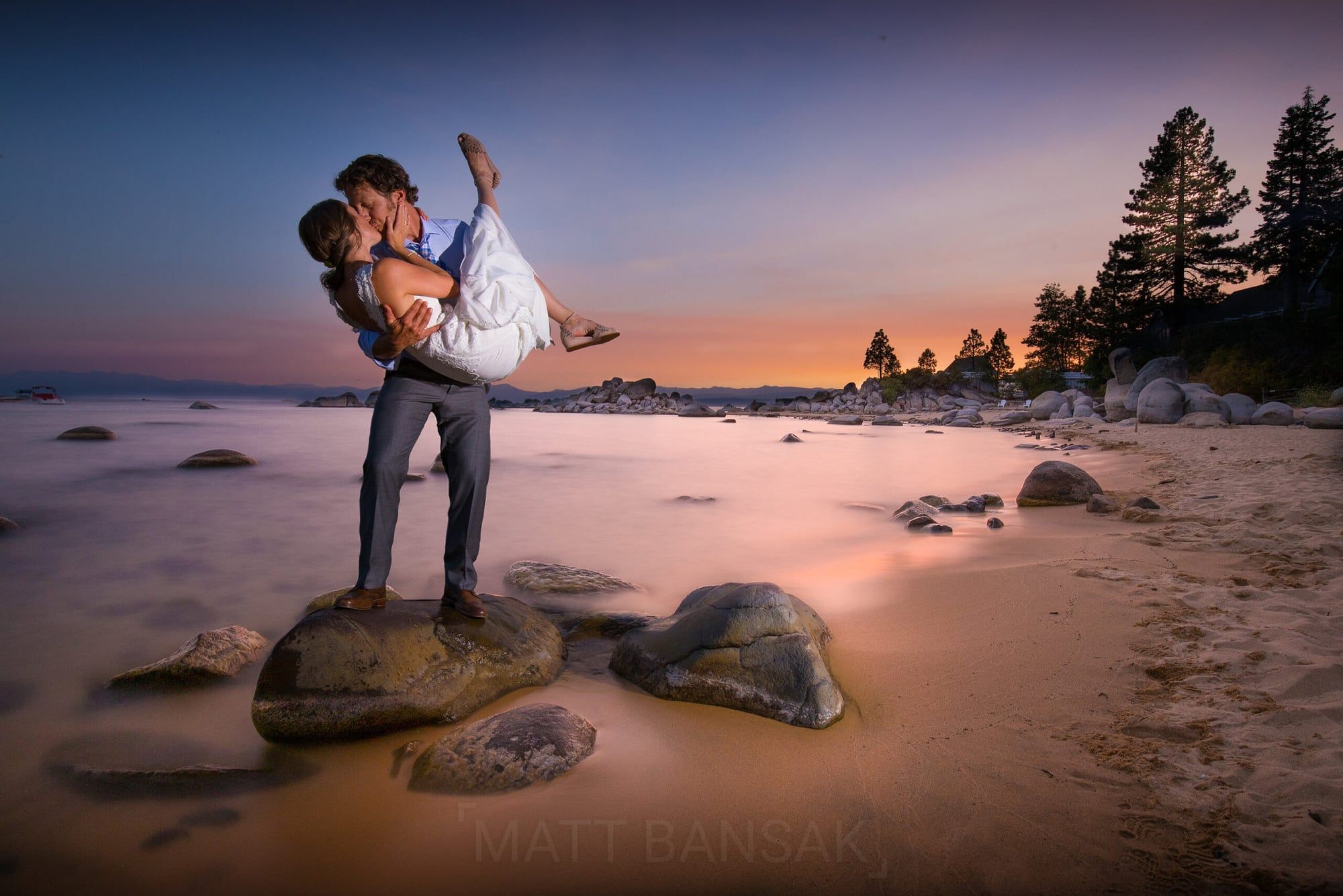 Couple kissing on a rock in Lake Tahoe at sunset